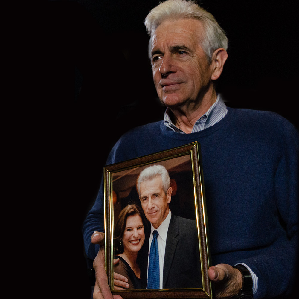 James Naughton holding a photo of he and his wife Pam